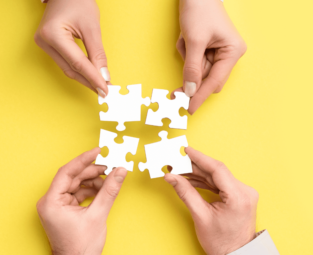 two people holding pieces of white puzzle pieces on a yellow background