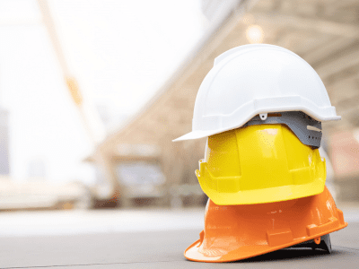 Hard hats stacked up in front of a building site to represent health and safety at work