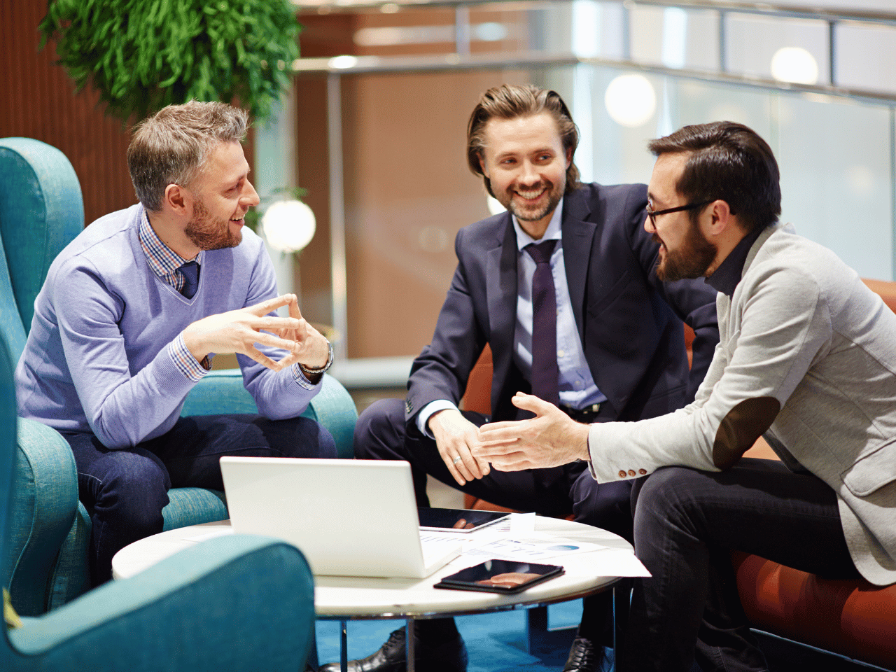 three men sit at a table discussing business