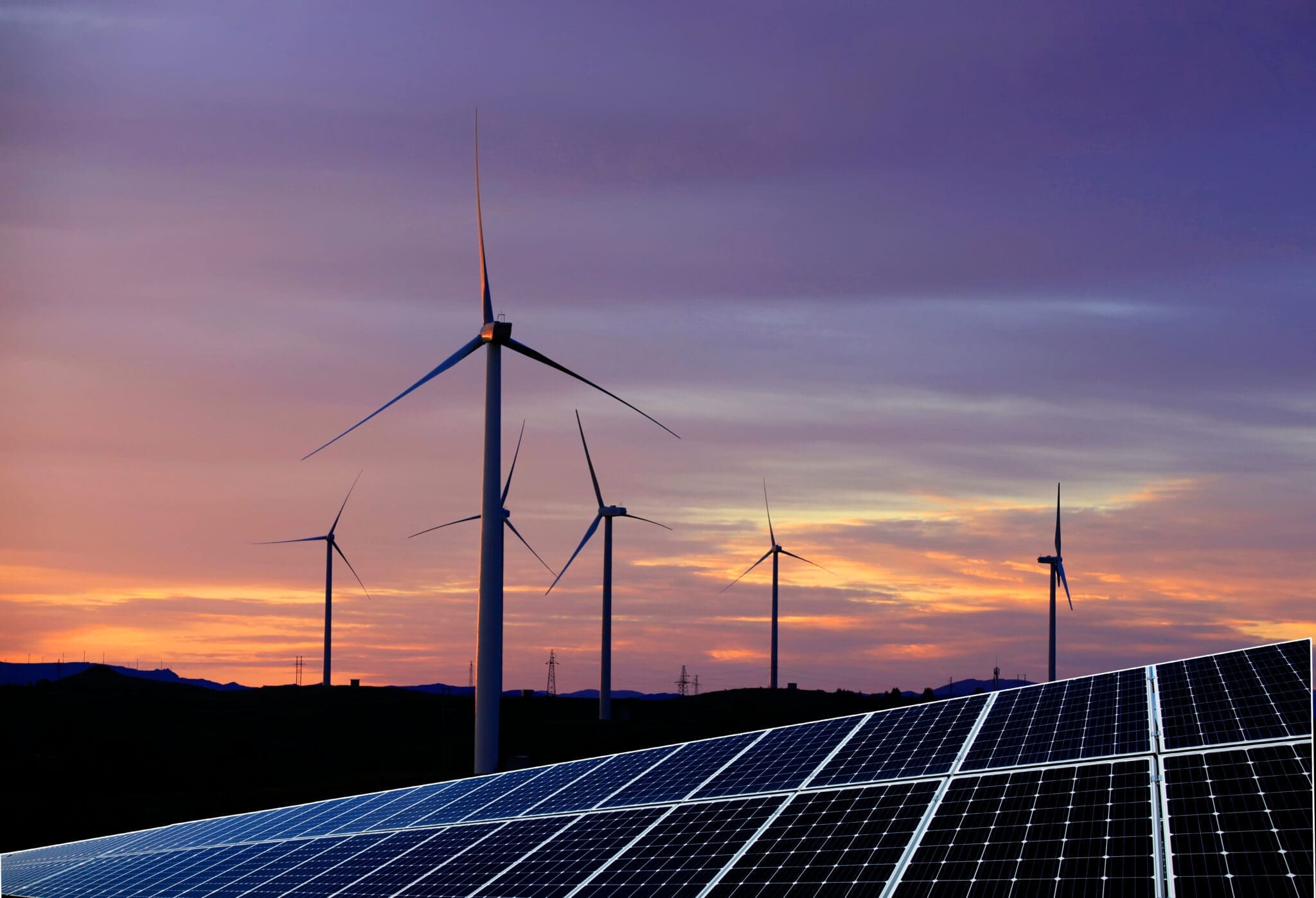 solar panels and wind turbines at sunset