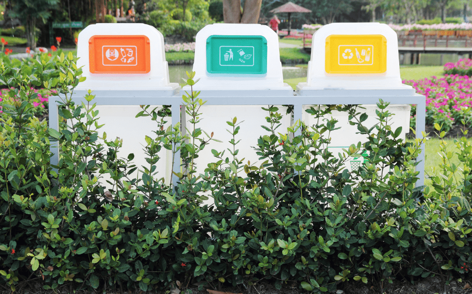 a row of colourful recycling bins in a park